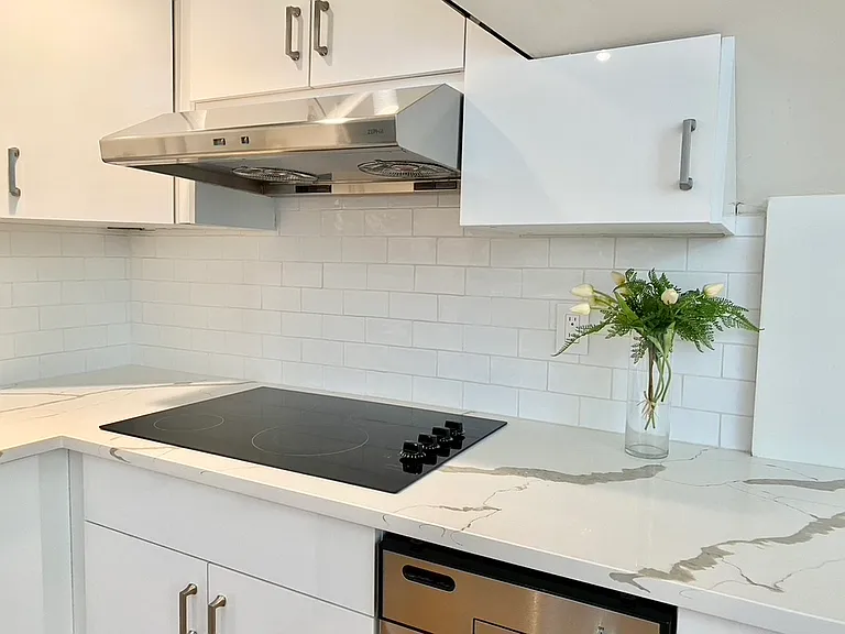 Sleek electric cooktop with elegant quartz-style countertops.
