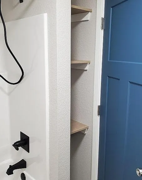 Linen storage behind door inside Primary Bath