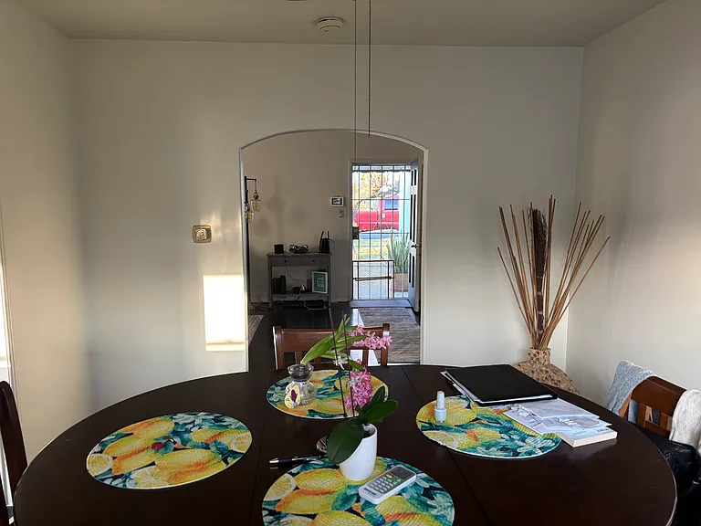 Bright and versatile nook area with ample space, seamlessly connecting to the entryway and overlooking a large, beautifully landscaped green yard.