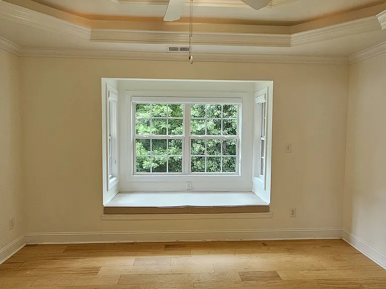 Primary suite offers a tray ceiling, abundant natural light, and a charming built-in window bench with storage.