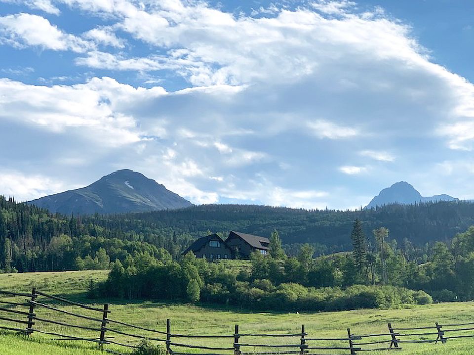 View of the house facing West from the range below. The house and property is backed by National Forrest and the trail and lake system into the Gore Range.