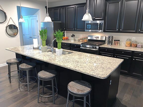 2nd floor open concept kitchen includes metal bar stools, stainless steel appliances, and small office next to panty.