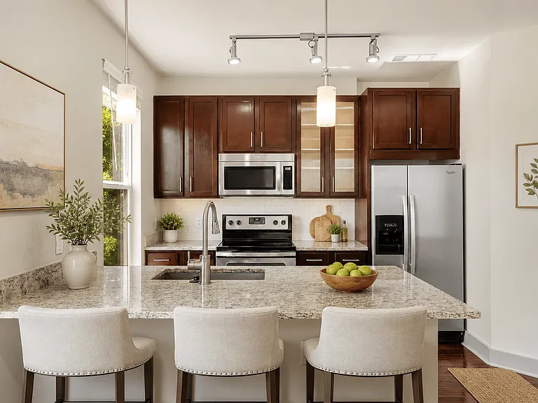 A kitchen with a granite countertop and white chairs.