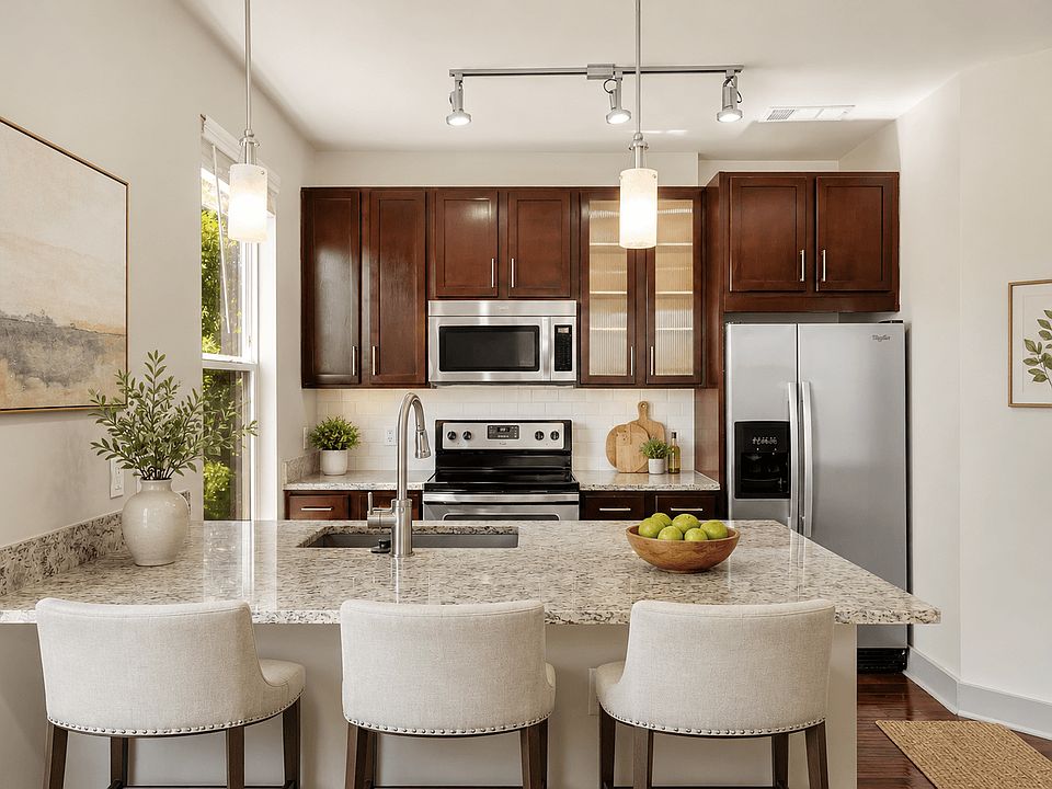 A kitchen with a granite countertop and white chairs.