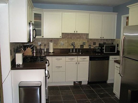 Recently renovated kitchen with new white cabinets, slate floors, Silestone(R) counters, tumbled marble backsplash, stainless appliances