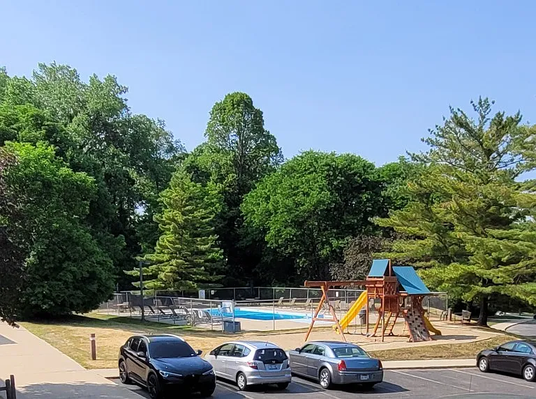 View from porch. Tree-lined children's play area and swimming pool.
