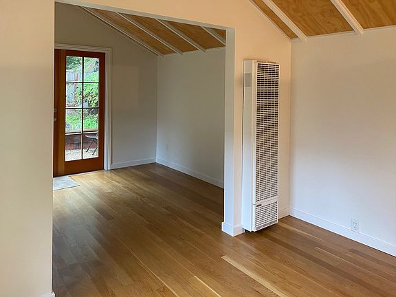 View from kitchen and dining into the front room with gas wall heater.