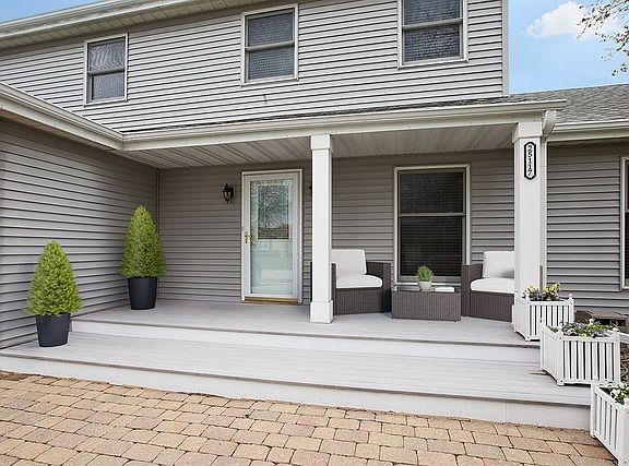 A large, covered front porch steps down onto a brick paver patio and sidewalk.  Perfect for those la