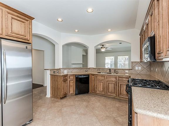 Large Kitchen looks into Living Room through center and right arch. Left arch leads to Entry Hallway. Dining Room located behind camera shot. Kitchen offers freshened up cabinets, Silestone countertops, tile backsplash, gas cooking, Pantry, eat-in Br