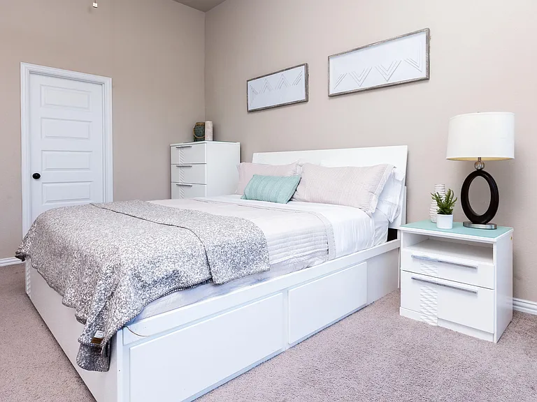 Furnished bedroom with a full bed, nightstand and dresser, plus under-bed storage for added organization.