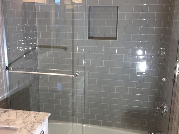 Back bedroom bath has shower over tub, single vanity.