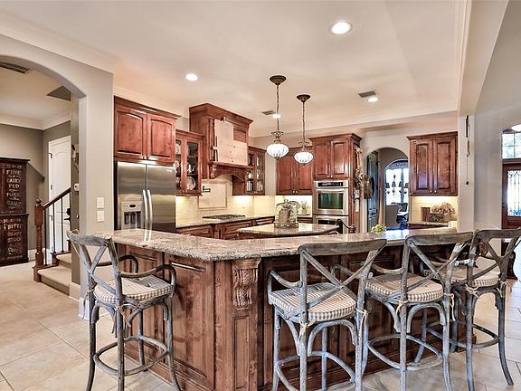 Kitchen (14.25x15) features stained cabinetry, Crema Bordeaux granite, stainless appliances including Bosch dishwasher, Viking 6 burner range, and KitchenAid double oven. To the left of the picture is the return staircase and back hallway towards the