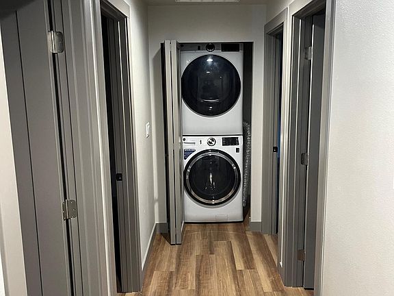 Hallway with laundry space with included stackable washer and dryer.