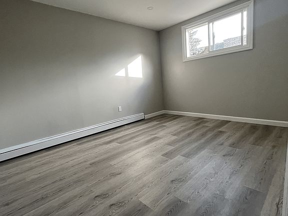 Spacious and bright bedroom featuring elegant flooring, recessed lighting, and a large window for natural light. A perfect space for rest and relaxation!