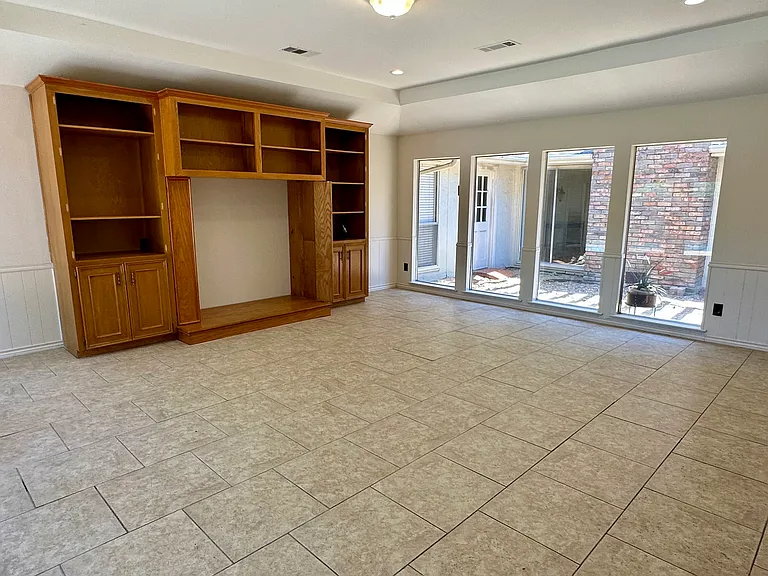 Family room area featuring light tile patterned flooring overlooking pool area with a raised ceiling.