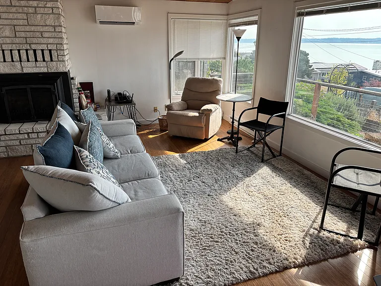 Living room with wall of windows and view of Sound and mountains.