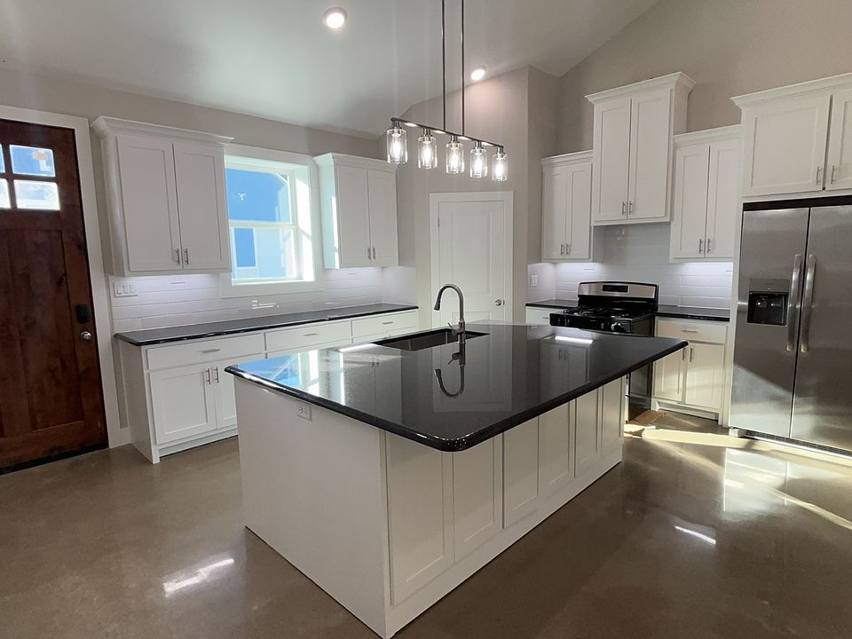Kitchen with granite countertops and undercabinet lighting. Walk in pantry in the corner. Island has over hang for bar stools