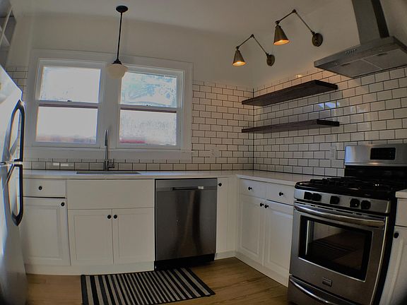 Kitchen with new stainless steel appliances, subway tile, original wood floor