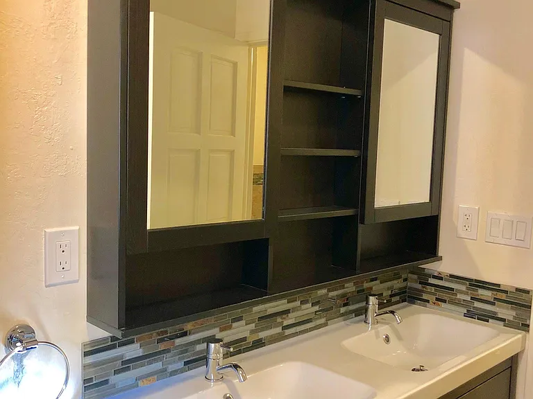 Downstairs bath with dual storage mirrors and shelves over dual sinks. Not seen in photos is linen closet behind entry door.