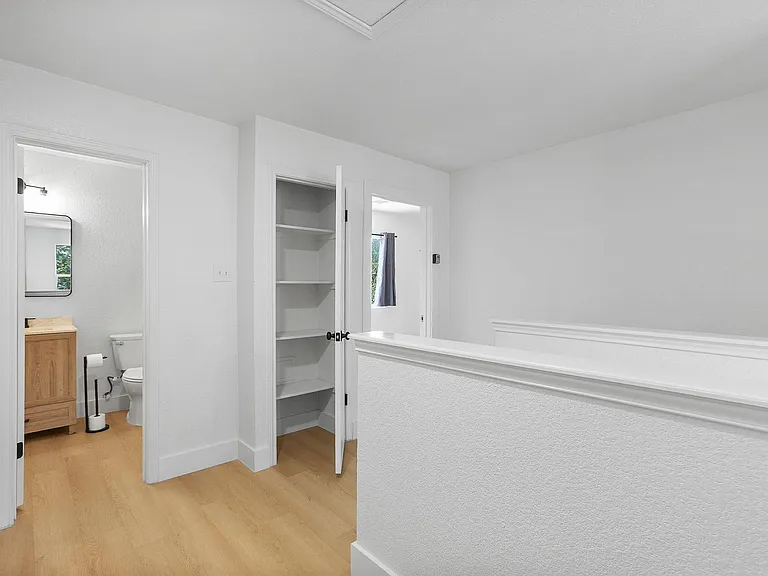 Upstairs landing with built-in shelving and quick access to a nearby bath; clean lines and hard-surface flooring.