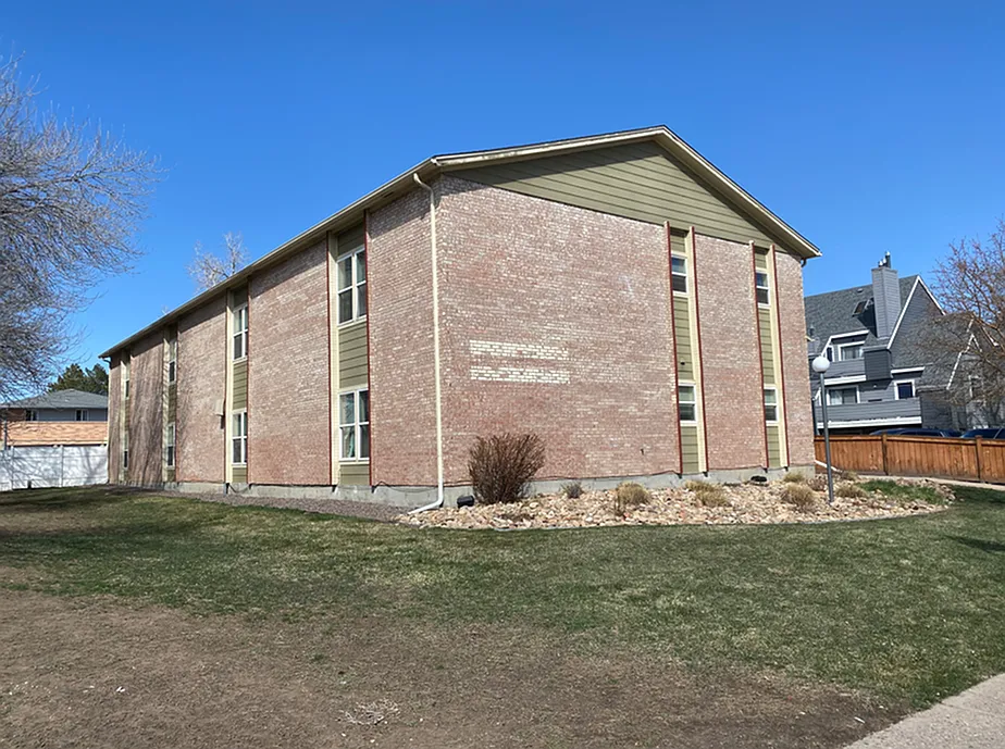Charming brick apartment building with well-manicured lawn and serene residential surroundings, perfect for comfortable living.