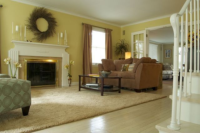 Spacious sun-filled Living Room w/pickled hardwood floor & fireplace.