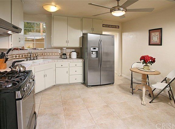 The cook in the family is going to truly appreciate the bright and spacious kitchens abundant cabinets that reach the ceiling, dual basin sink, tiled counters with full mosaic inlaid custom tiled backsplash, lighted ceiling fan and easy care tile floor.