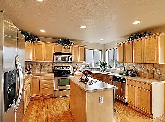 Large island kitchen with lots of natural maple cabinets & light oak flooring