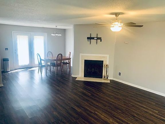Lower level view: Open floorplan w/ Living room, dining area, gas fireplace, brackets for flat screen tv, backdoor, ceiling fan, hardwood floors throughout lower level. Great natural light.