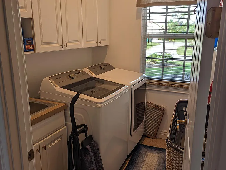 Laundry Room. Includes new washer, electric dryer, utility sink, storage, fold-down ironing board, air-drying rack and window overlooking the front door approach.