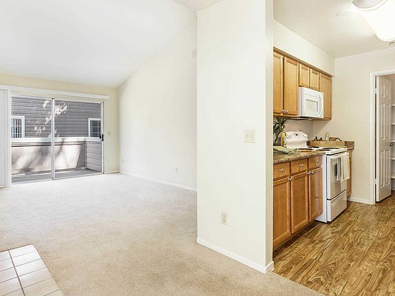Kitchen and Carpeted Living Room with Balcony