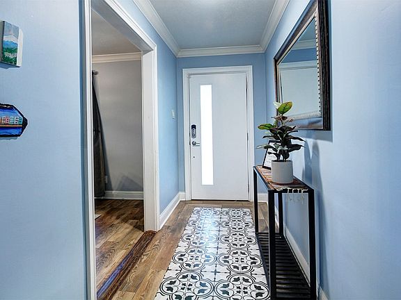 Love the mosaic inlaid tile foyer. Paint color brings out the blue in- the floor tiles. Note: walls had all texture removed and freshly painted  for a smoother look. Redid transition pieces 2024.