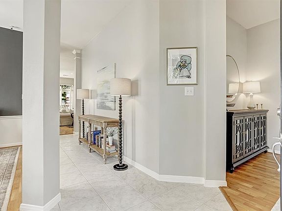An impressive entry with a soaring ceiling with a modern chandelier, tile floors, and soft neutral paint greets visitors as they enter. An elegant formal dining room is to the right and a spacious formal living to the left.