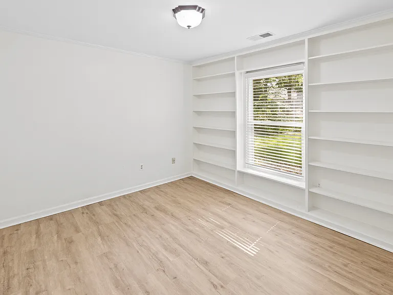 Versatile room with stunning floor-to-ceiling built-in shelving _ ideal as a home office, library, or study.