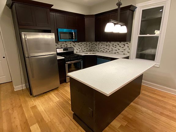 Side view of contemporary kitchen cabinetry, brand new stainless steel appliances with quartz counter tops