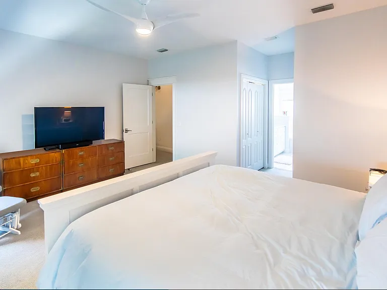 Master bedroom has a smart TV, a dresser and a lounge chair.