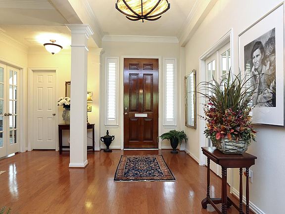 A classic large foyer with thick crown molding, a column, wood stained door with side lights and dec