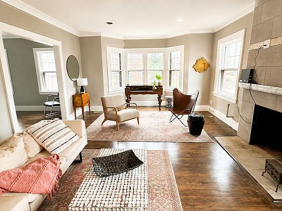 Spacious living room with bay windows, hardwood floors, and a tiled fireplaceideal for relaxing or entertaining.