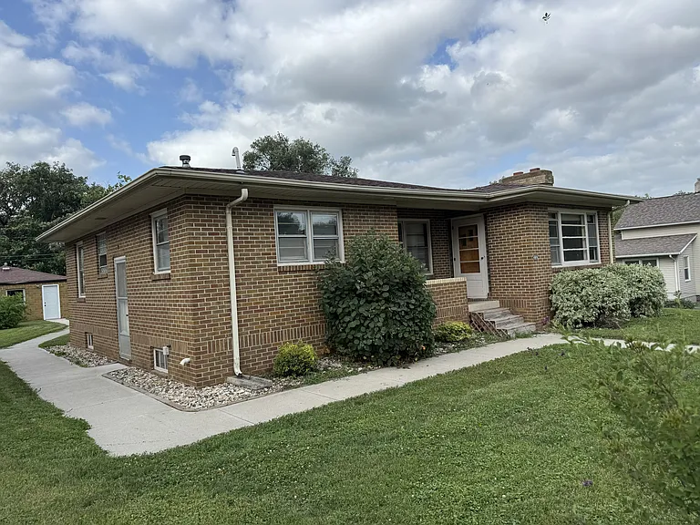 Front of house. Side door and sidewalk out to two car detached garage/workshop