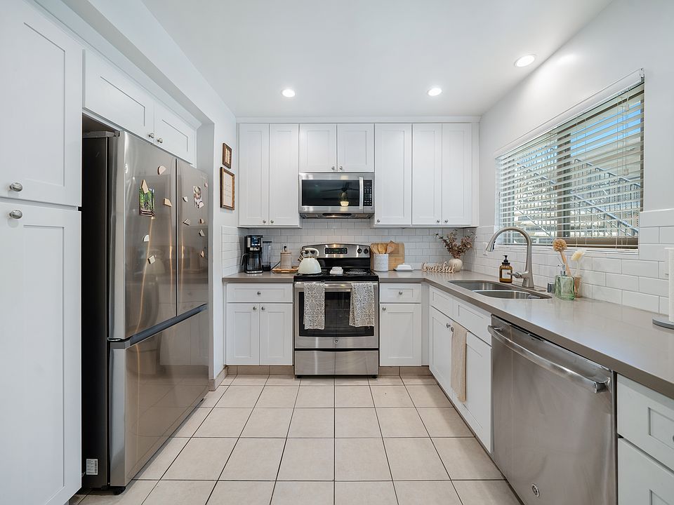#12 Kitchen- stainless steel electric stove, dishwasher & microwave. Gray quartz countertop, white cabinetry Recessed ceiling lights & tile floor.
Horizontal blinds