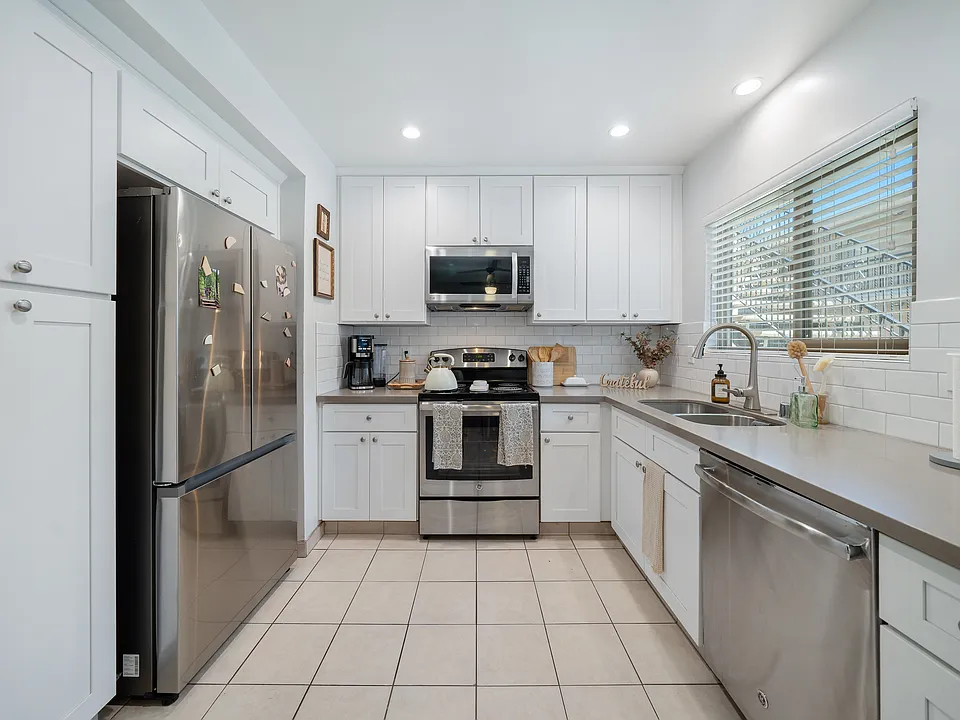 #12 Kitchen- stainless steel electric stove, dishwasher & microwave. Gray quartz countertop, white cabinetry Recessed ceiling lights & tile floor.
Horizontal blinds