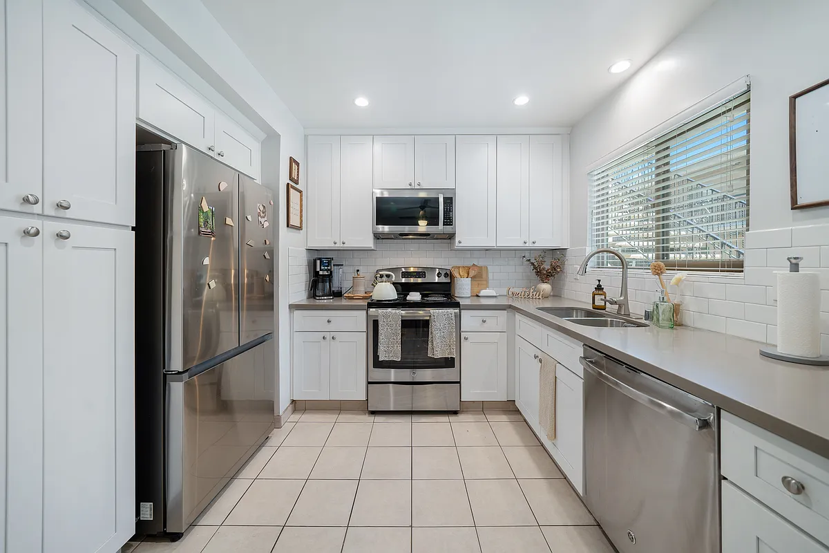 #12 Kitchen- stainless steel electric stove, dishwasher & microwave. Gray quartz countertop, white cabinetry Recessed ceiling lights & tile floor.
Horizontal blinds - La Casa de la Reina
