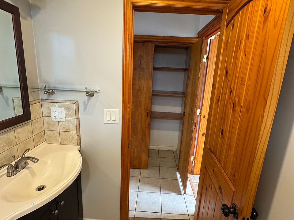 Bathroom showing closet in the hallway, porcelain tiles in the bathroom. Two panel pine solid wood clear stain bathroom door.