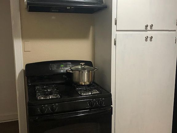 Gas range stove with refrigerator on the other side of the cabinet.