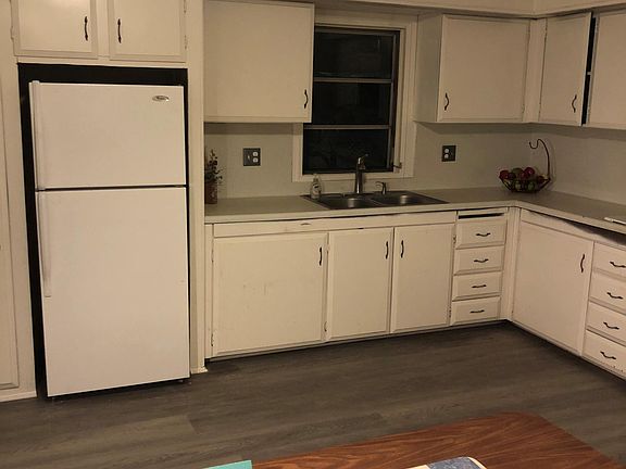Kitchen includes refrigerator with stainless steel double sinks.