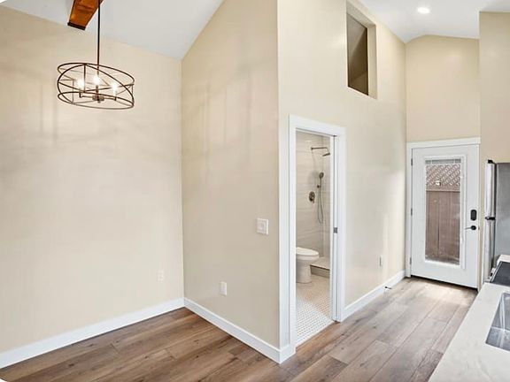 Vaulted ceiling , front door, bathroom with storage above, open kitchen/ living area design.