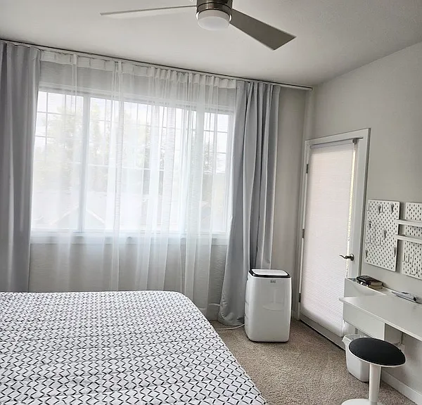 Primary bedroom with portable A/C, ceiling fan, and private balcony access