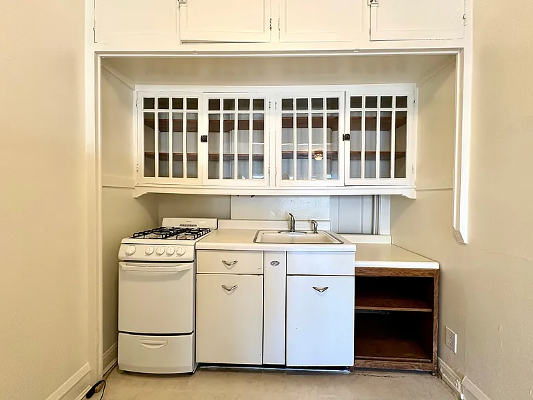Charming vintage kitchen with built-in shelving, gas stove, and classic white cabinetry. Charming vintage kitchen with built-in shelving, gas stove, and classic white cabinetry.