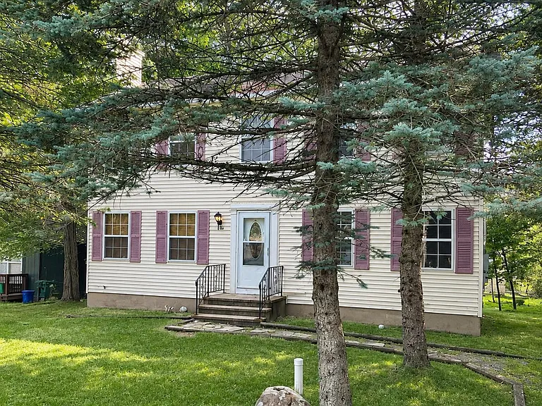 Spacious front lawn with beautiful shade trees and a welcoming entrance