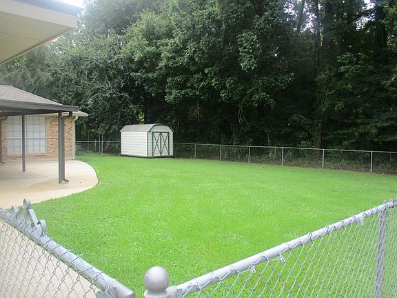 Fenced back yard with storage building.
